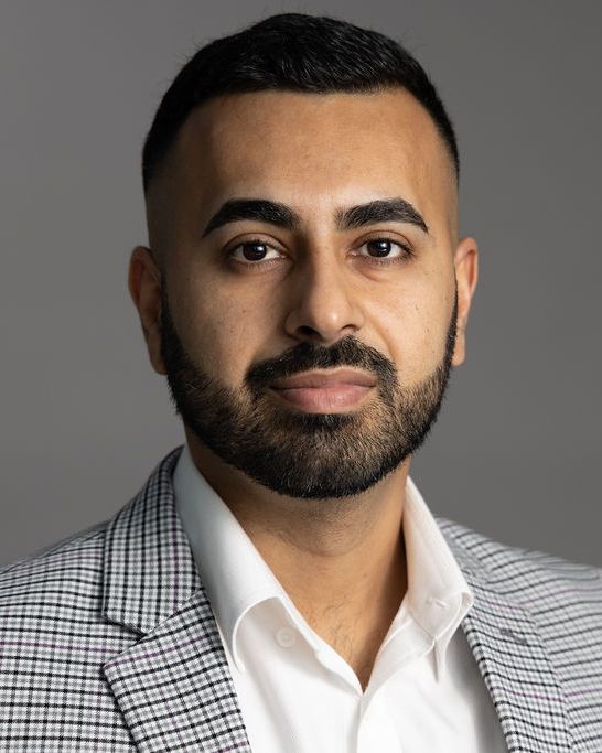 Studio headshot, houndstooth blazer, gray backdrop